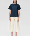 Person wearing a navy blue t-shirt and beige pants on a white background
