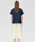 Person wearing a navy blue shirt and light-colored pants on a white background