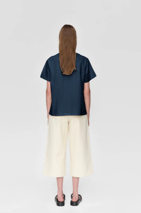 Person wearing a navy blue shirt and light-colored pants on a white background