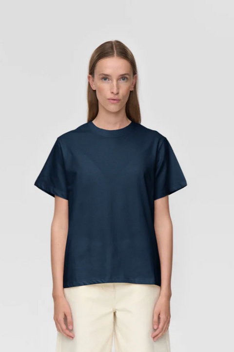 Woman wearing a navy blue t-shirt against a light gray background