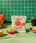Packaged apple fries with apples and coffee on a green table