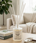 Candle with diffuser sticks on a coffee table in a living room setting