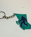 Keychain with a silhouette of a bigfoot inside the outline of British Columbia on a light background