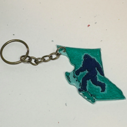 Keychain with a silhouette of a bigfoot inside the outline of British Columbia on a light background