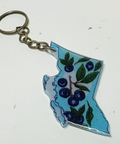 Keychain shaped like the outline of British Columbia with blueberries and leaves on a white background