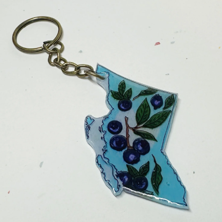 Keychain shaped like the outline of British Columbia with blueberries and leaves on a white background