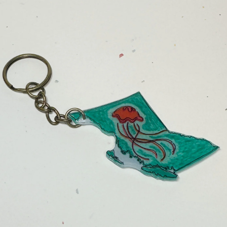 Keychain shaped like the state of British Columbia with a red flower on a white background