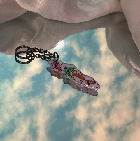 Keychain with cartoon design held by a hand against a cloudy sky background