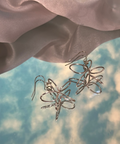 Silver floral earrings on a soft fabric background