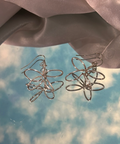 Silver wire flower earrings on a soft fabric background
