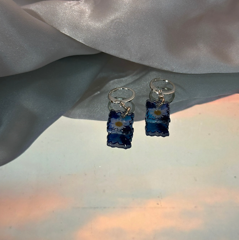 Pair of blue floral earrings on a light fabric background