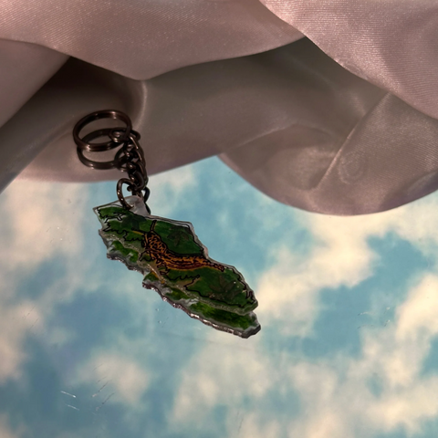 Keychain with a green leaf design against a cloudy sky