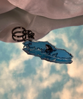 Blue whale skeleton keychain against a cloudy sky background