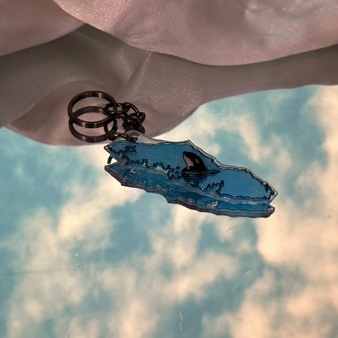 Blue whale skeleton keychain against a cloudy sky background