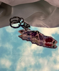 Decorative keychain with floral design against a cloudy sky background