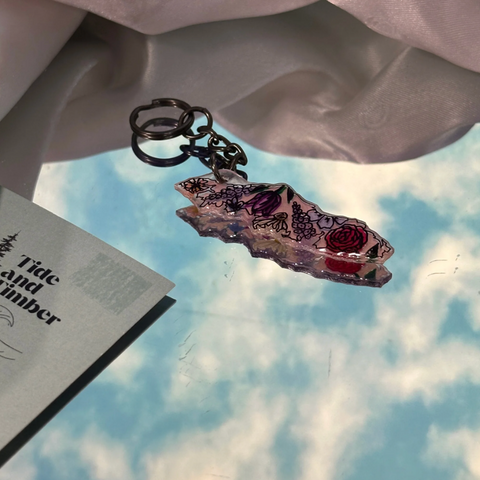 Decorative keychain on a surface with a magazine titled 'Tide and Timber' in the background.