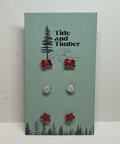 Set of earrings on a Tide and Timber branded card with trees and nature design.