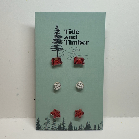 Set of earrings on a Tide and Timber branded card with trees and nature design.