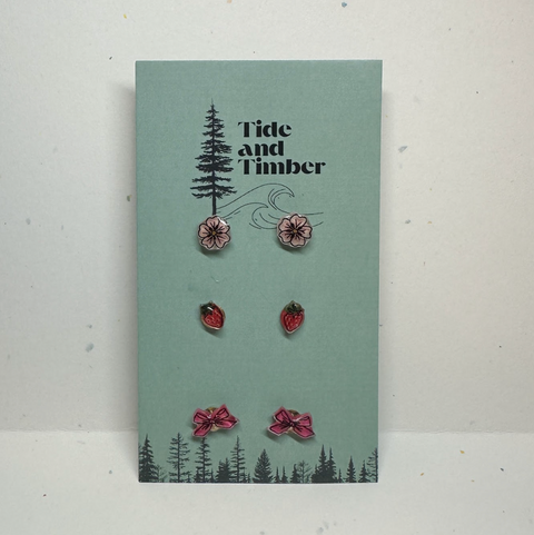 Set of earrings on a 'Tide and Timber' branded card with tree and flower designs.