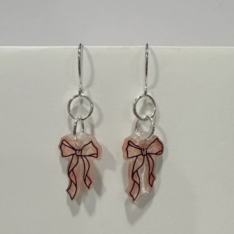 Earrings with bow designs on a light gray background