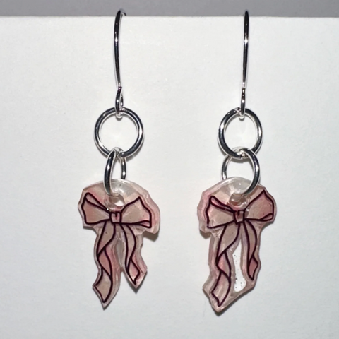 Pair of earrings with bow design on a light gray background