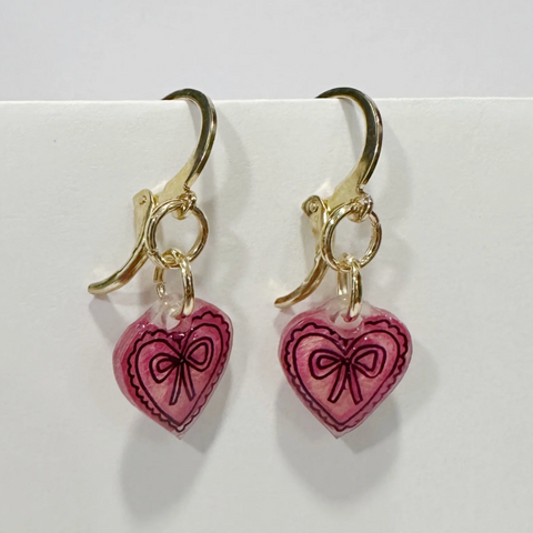 Heart-shaped earrings with pink hearts and gold accents on a white background