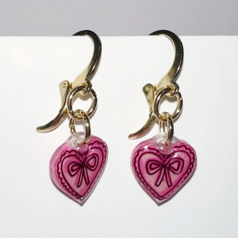 Pair of earrings with pink heart-shaped charms on a white background