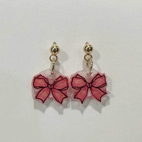 Pair of earrings with pink bow designs on a light gray background