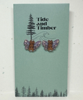 Earrings with animal designs on a card labeled 'Tide and Timber' against a light gray background.