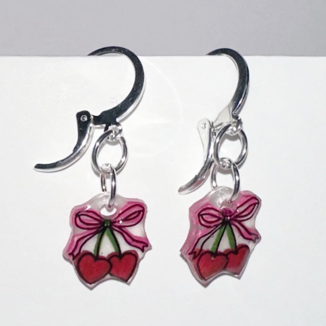 Handmade earrings with cherry designs on a white background