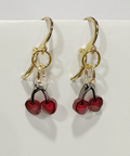 Handmade earrings with red berry charms on a light gray background