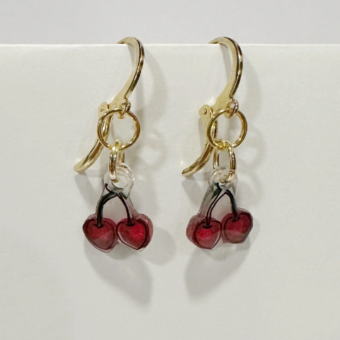 Handmade earrings with red berry charms on a light gray background