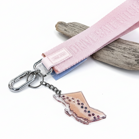 Keychain with pink ribbon and carabiner on a wooden surface