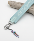 Keychain with a light blue strap and colorful charm on a wooden surface