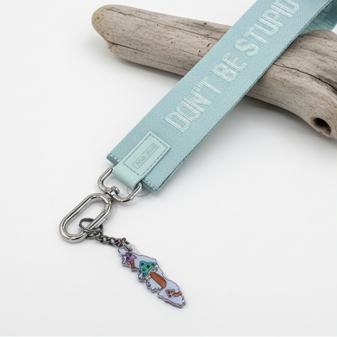 Keychain with a light blue strap and colorful charm on a wooden surface