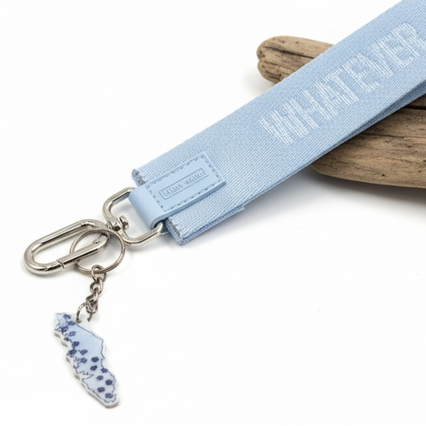 Light blue keychain with 'WHATEVER' text on a wooden surface