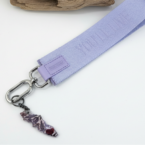 Lavender keychain strap with a small charm on a wooden surface