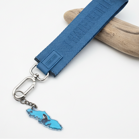 Blue keychain with a map charm on a wooden surface