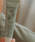 Skincare cream tube labeled 'SKWÚllen' held by a hand against a blurred background