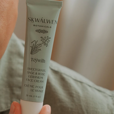 Skincare cream tube labeled 'SKWÚllen' held by a hand against a blurred background