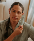Man holding a skincare product in a casual indoor setting