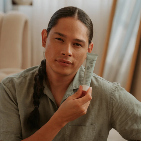 Man holding a skincare product in a casual indoor setting