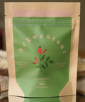 Tea package with green label and brown paper sleeve on a blurred background