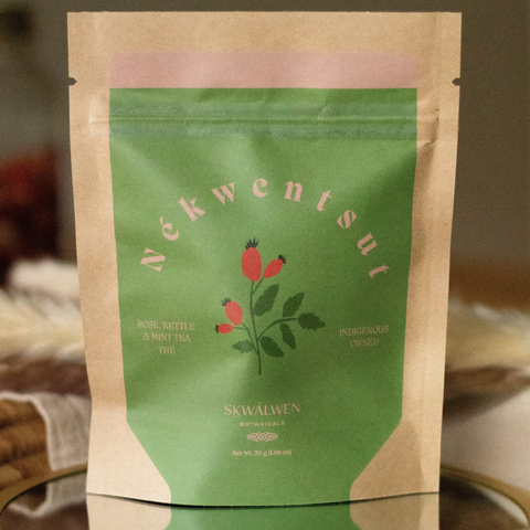 Tea package with green label and brown paper sleeve on a blurred background