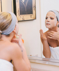 Woman applying a face mask in front of a mirror