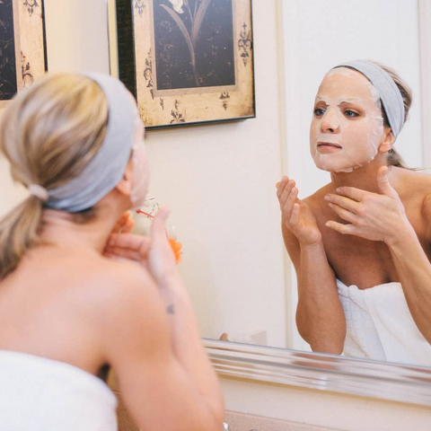 Woman applying a face mask in front of a mirror