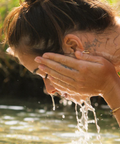 Person washing their face with water outdoors