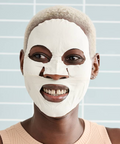 Person wearing a white face mask against a light blue background