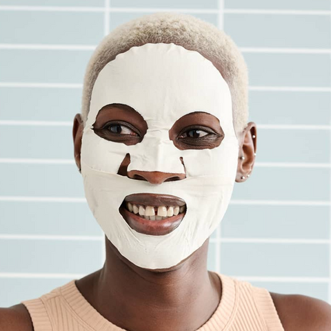 Person wearing a white face mask against a light blue background