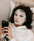 Woman with a face mask using a phone on a couch